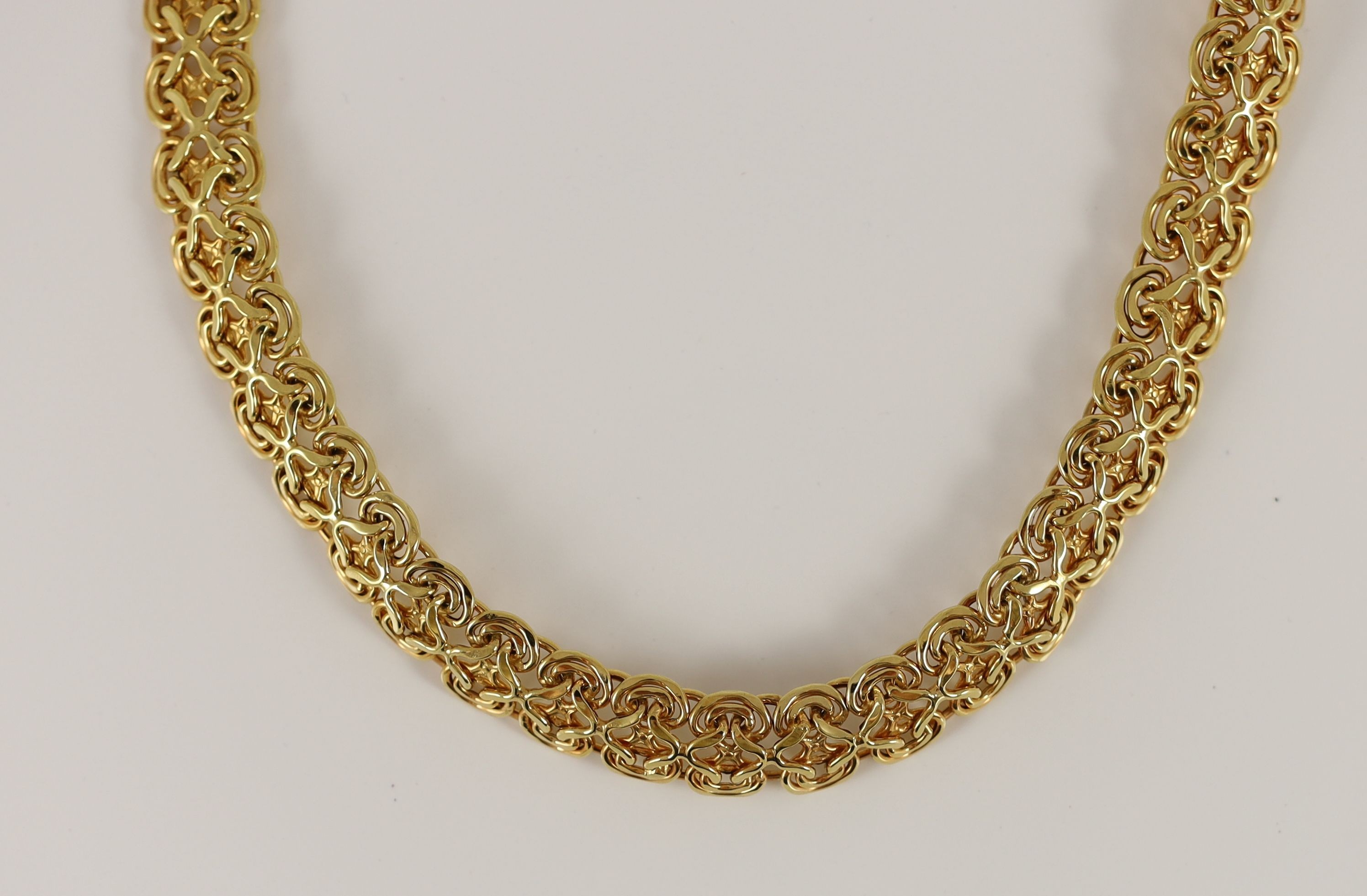 A modern 14k gold pierced scroll link necklace